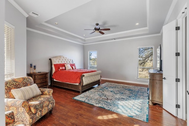 bedroom with multiple windows, a tray ceiling, and wood finished floors