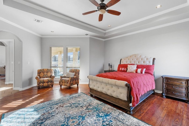 bedroom featuring arched walkways, visible vents, ornamental molding, and hardwood / wood-style floors