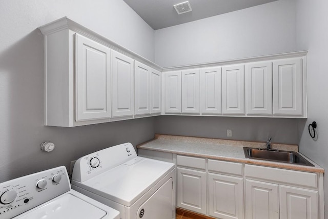 clothes washing area featuring cabinet space, visible vents, washing machine and dryer, and a sink