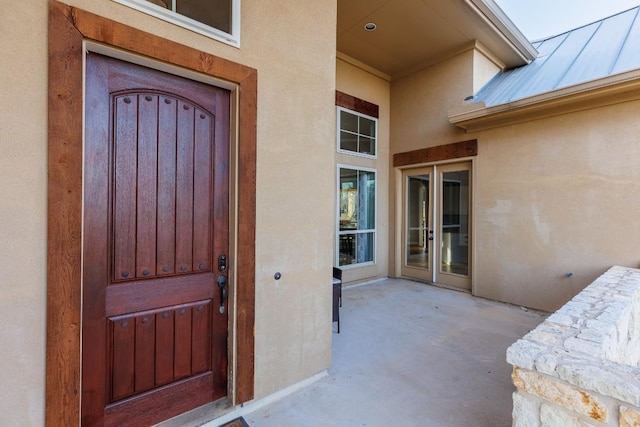 view of exterior entry featuring stucco siding and a patio