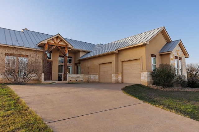 3206 Douglas Dr, Horseshoe Bay, TX 78657 - view of front facade featuring a standing seam roof, metal roof, a garage, stone siding, and driveway