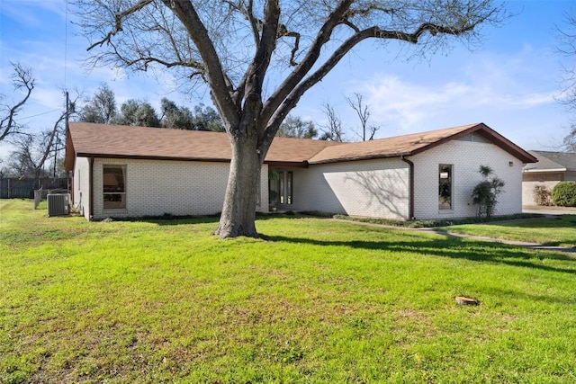 view of front of home featuring a front yard, cooling unit, and brick siding