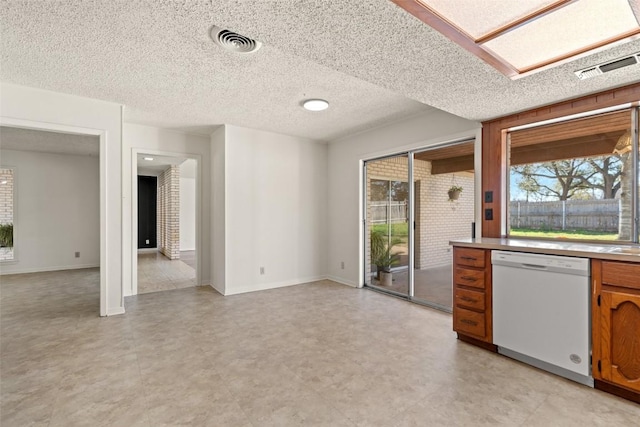 kitchen featuring plenty of natural light, brown cabinets, dishwasher, and visible vents