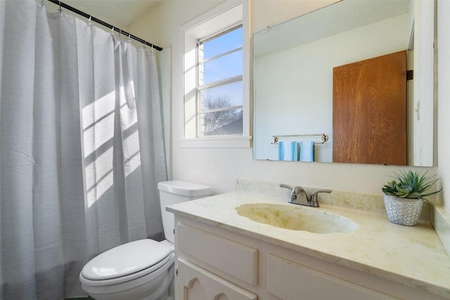 bathroom with curtained shower, toilet, and vanity