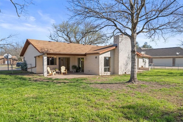 back of house with a lawn, fence, brick siding, a chimney, and a patio area