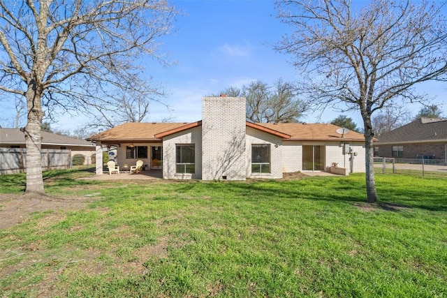 back of property featuring a patio area, a lawn, a chimney, and a fenced backyard