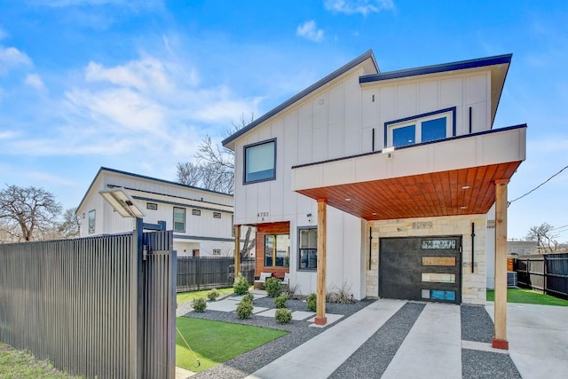 view of front of property with board and batten siding, driveway, a garage, and fence