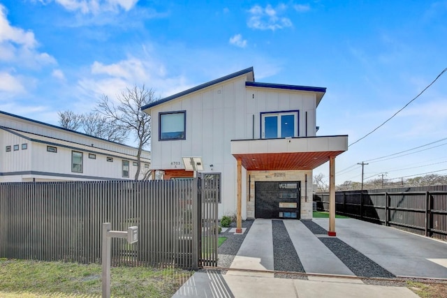 view of front of home with a fenced front yard, board and batten siding, concrete driveway, and an attached garage