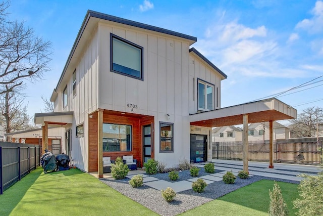 back of property featuring board and batten siding, a yard, and fence