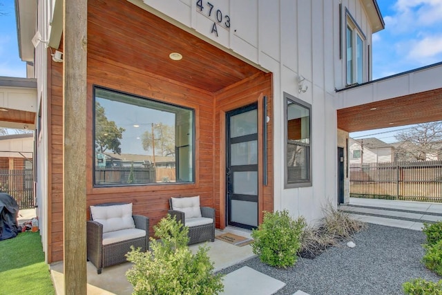 view of exterior entry with fence and board and batten siding