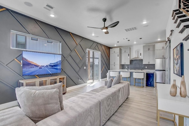 living room featuring visible vents, ceiling fan, and light wood finished floors