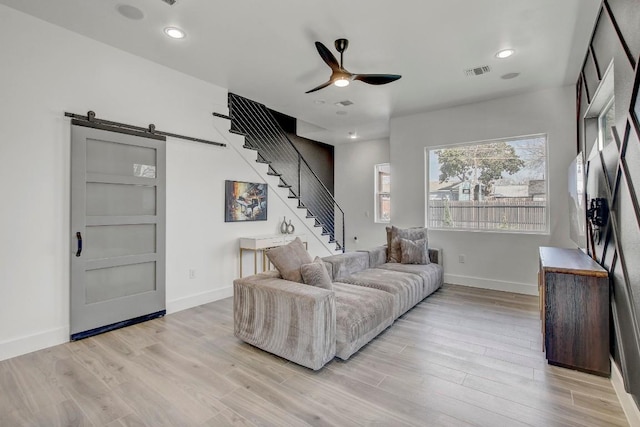 living room featuring light wood-type flooring, visible vents, a ceiling fan, and stairway