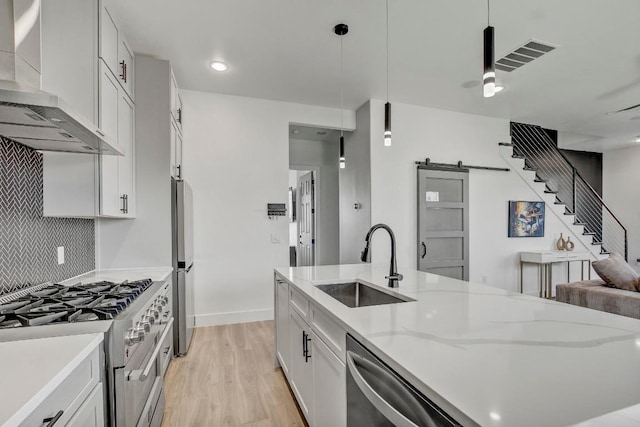 kitchen with tasteful backsplash, visible vents, wall chimney range hood, appliances with stainless steel finishes, and a sink