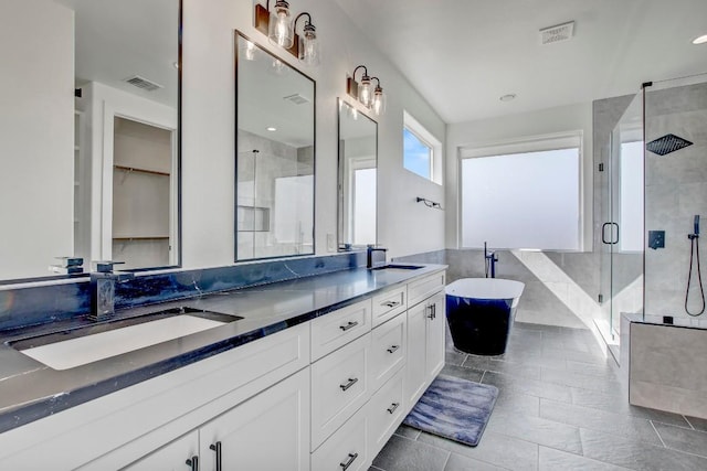 full bath with double vanity, visible vents, a stall shower, and a sink