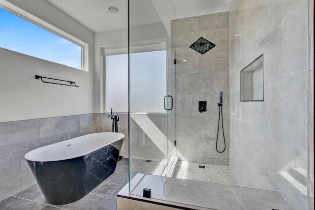 full bath with tile patterned floors, a shower stall, tile walls, and a freestanding tub