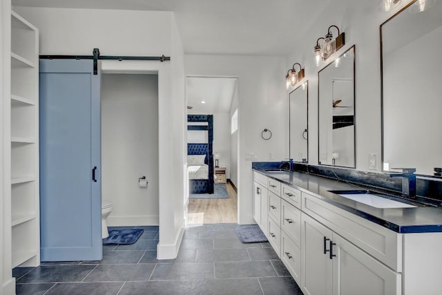 bathroom with double vanity, toilet, ensuite bath, and a sink