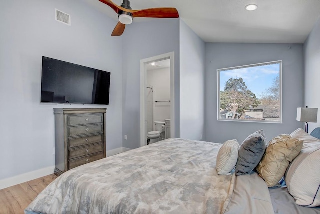 bedroom featuring wood finished floors, visible vents, baseboards, vaulted ceiling, and connected bathroom