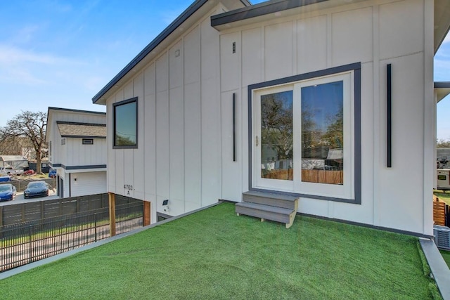 view of side of property with a yard, fence, and board and batten siding