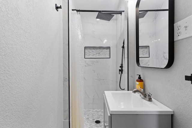 full bathroom featuring a marble finish shower, vanity, and a textured wall