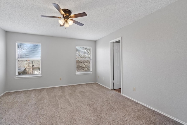 carpeted spare room featuring baseboards, a textured ceiling, and ceiling fan