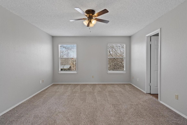 carpeted spare room featuring a textured ceiling, a textured wall, baseboards, and ceiling fan