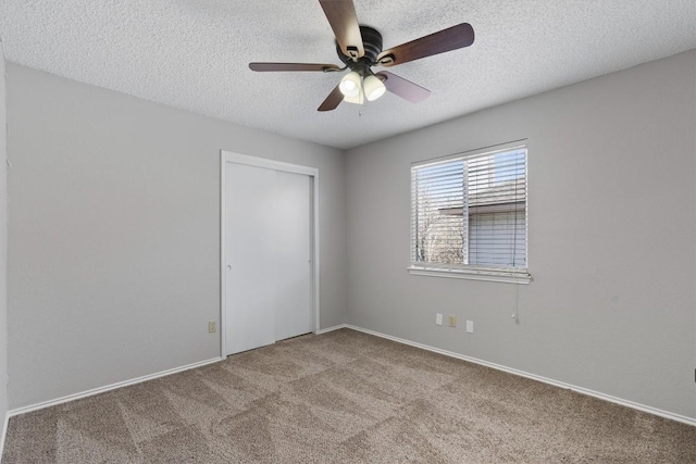 unfurnished bedroom featuring a closet, ceiling fan, a textured ceiling, and carpet