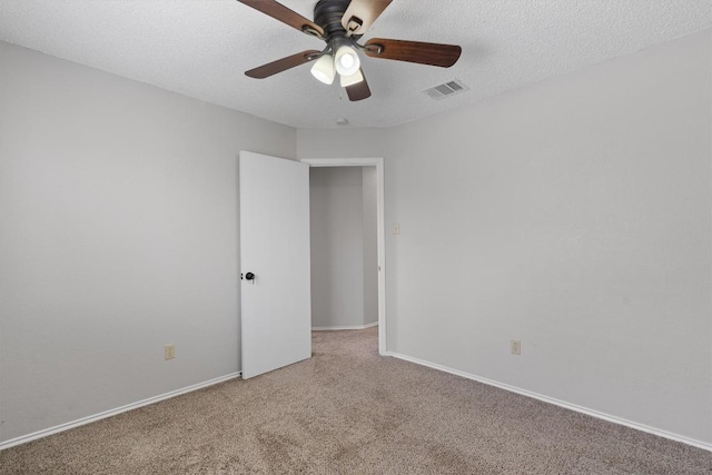 carpeted spare room featuring visible vents, baseboards, a textured ceiling, and a ceiling fan