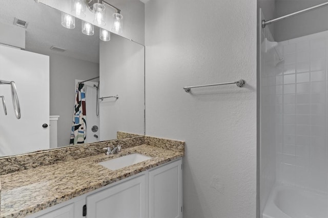 bathroom with vanity, shower / bath combo with shower curtain, a textured wall, and visible vents