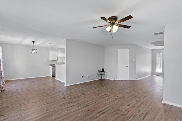 unfurnished living room featuring visible vents, baseboards, dark wood-type flooring, and ceiling fan