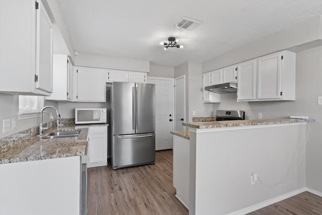 kitchen featuring visible vents, a sink, under cabinet range hood, appliances with stainless steel finishes, and white cabinetry