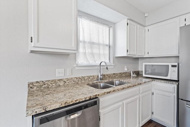 kitchen with white cabinets, light stone countertops, appliances with stainless steel finishes, and a sink