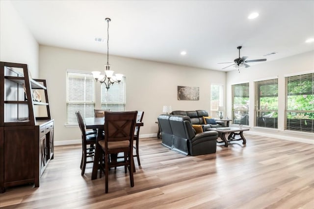 dining space with visible vents, baseboards, ceiling fan with notable chandelier, and light wood finished floors