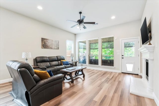 living area featuring light wood-type flooring, visible vents, plenty of natural light, and a ceiling fan