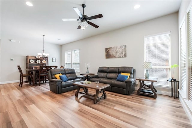 living area with recessed lighting, ceiling fan with notable chandelier, baseboards, and light wood-style floors