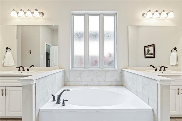 bathroom featuring a healthy amount of sunlight, a garden tub, and two vanities