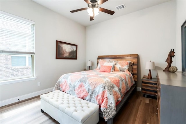 bedroom featuring visible vents, baseboards, wood finished floors, and a ceiling fan