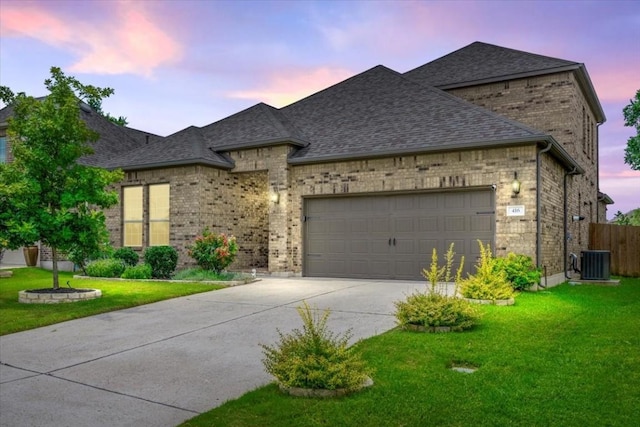 french country inspired facade featuring concrete driveway, an attached garage, a lawn, and brick siding