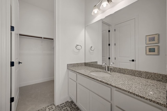 bathroom featuring vanity, a walk in closet, and baseboards