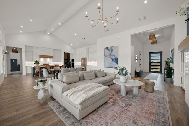 living room featuring wood finished floors, visible vents, high vaulted ceiling, beamed ceiling, and a notable chandelier