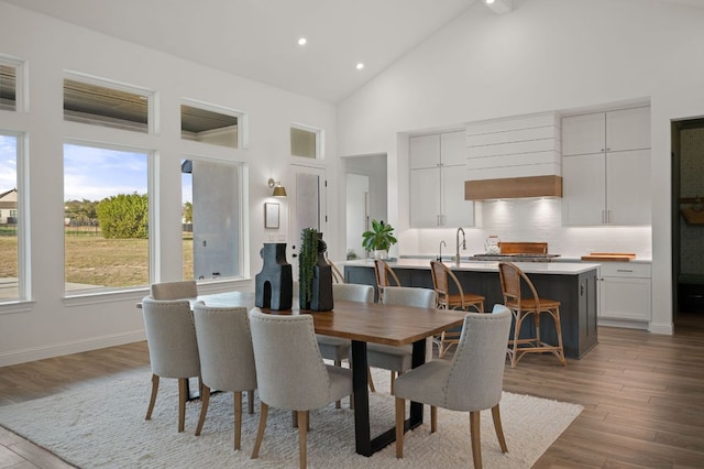 dining room featuring recessed lighting, baseboards, light wood-style floors, and high vaulted ceiling