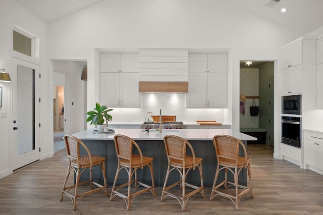 kitchen with built in microwave, light countertops, oven, and wood finished floors