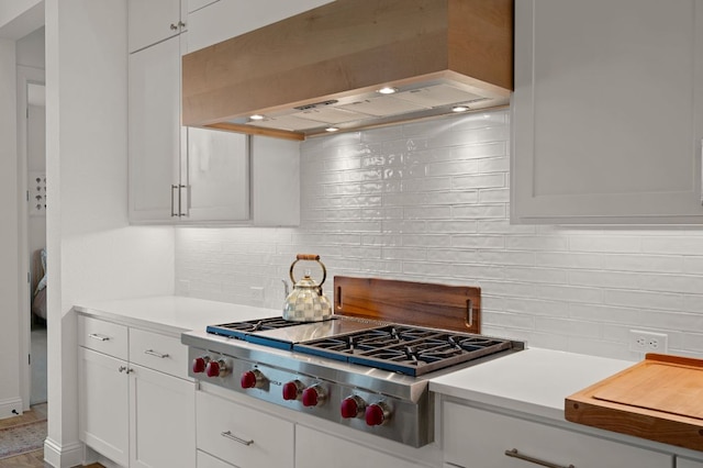 kitchen featuring tasteful backsplash, custom exhaust hood, light countertops, and stainless steel gas cooktop