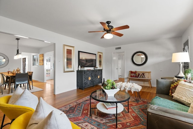 living area with visible vents, a ceiling fan, and wood finished floors