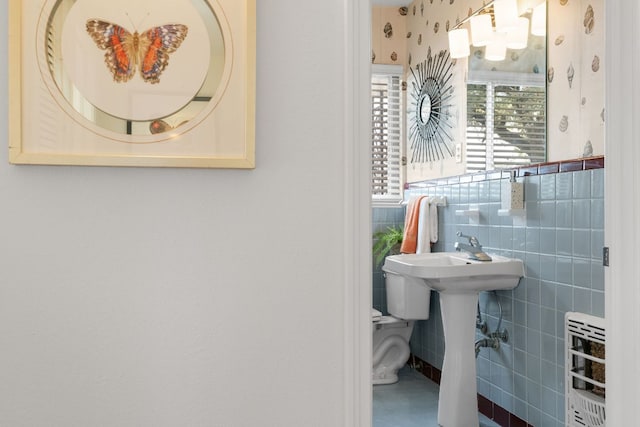 half bathroom with toilet, radiator, tile walls, and a sink