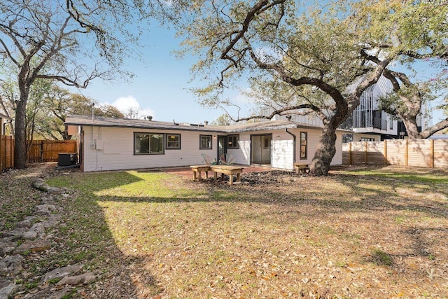 back of property featuring central AC unit, a lawn, and a fenced backyard