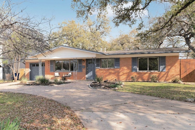 ranch-style house featuring brick siding, a front lawn, fence, a garage, and driveway