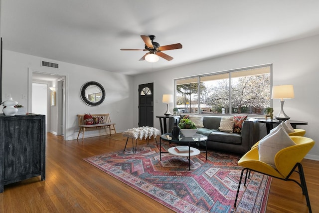 living area featuring visible vents, baseboards, ceiling fan, and wood finished floors