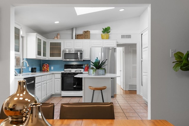 kitchen featuring light countertops, light tile patterned floors, white cabinets, stainless steel appliances, and a sink