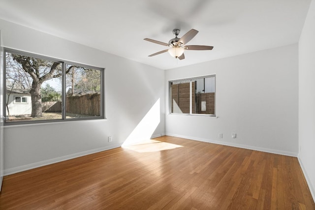 spare room with a ceiling fan, wood finished floors, and baseboards