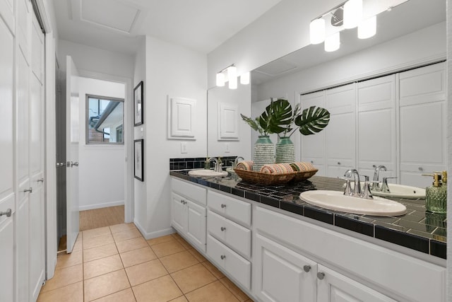 full bath featuring a sink, baseboards, double vanity, and tile patterned floors